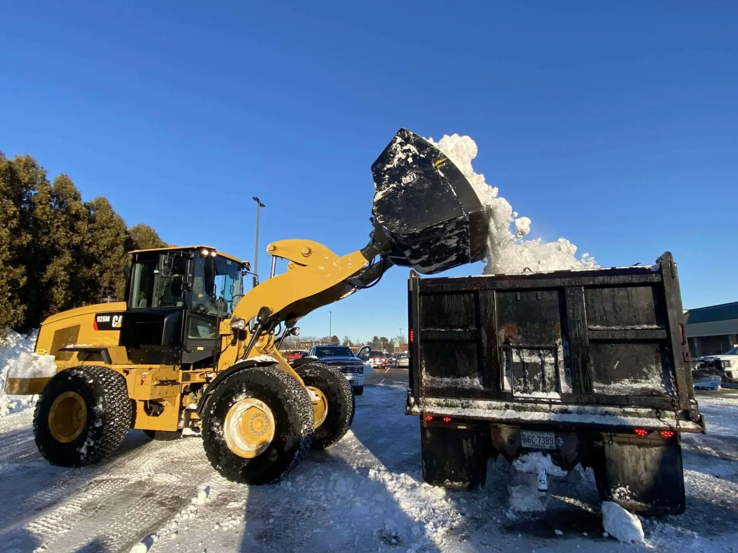 Loader dumping snow into a truck.