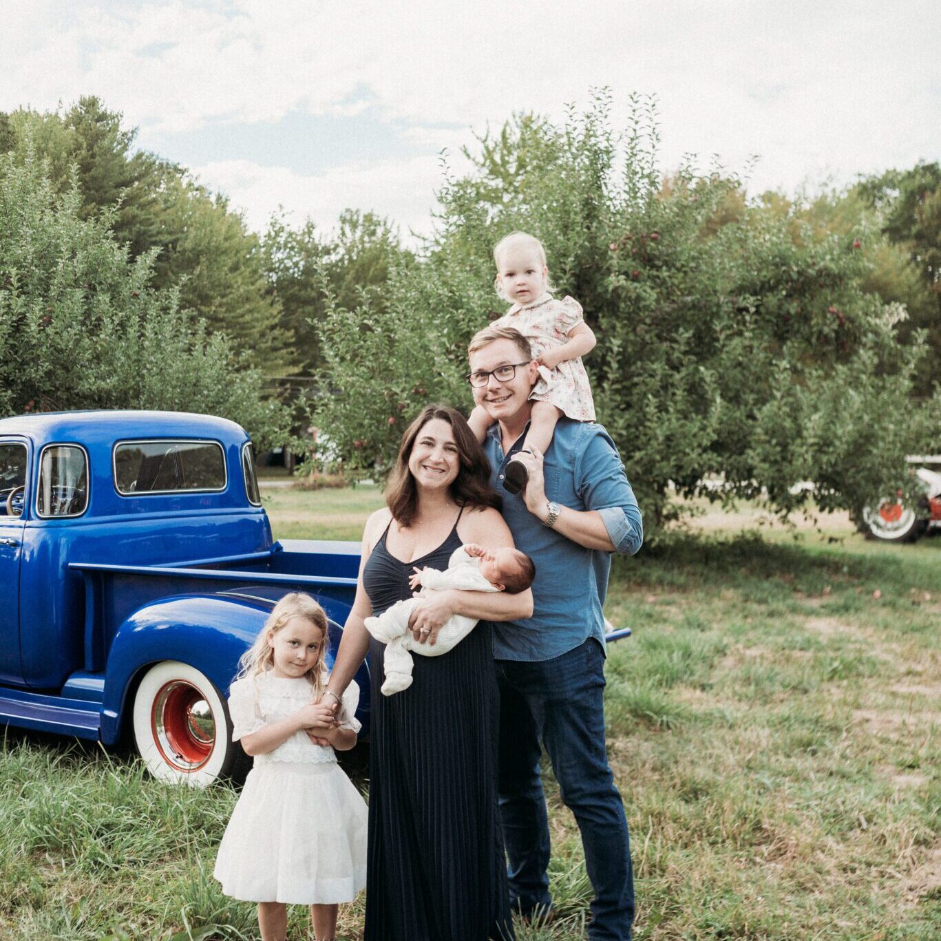 Family posing by vintage blue truck.