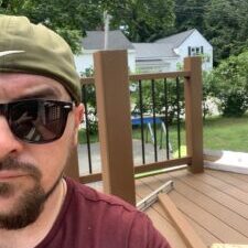 Man wearing sunglasses on a wooden deck.